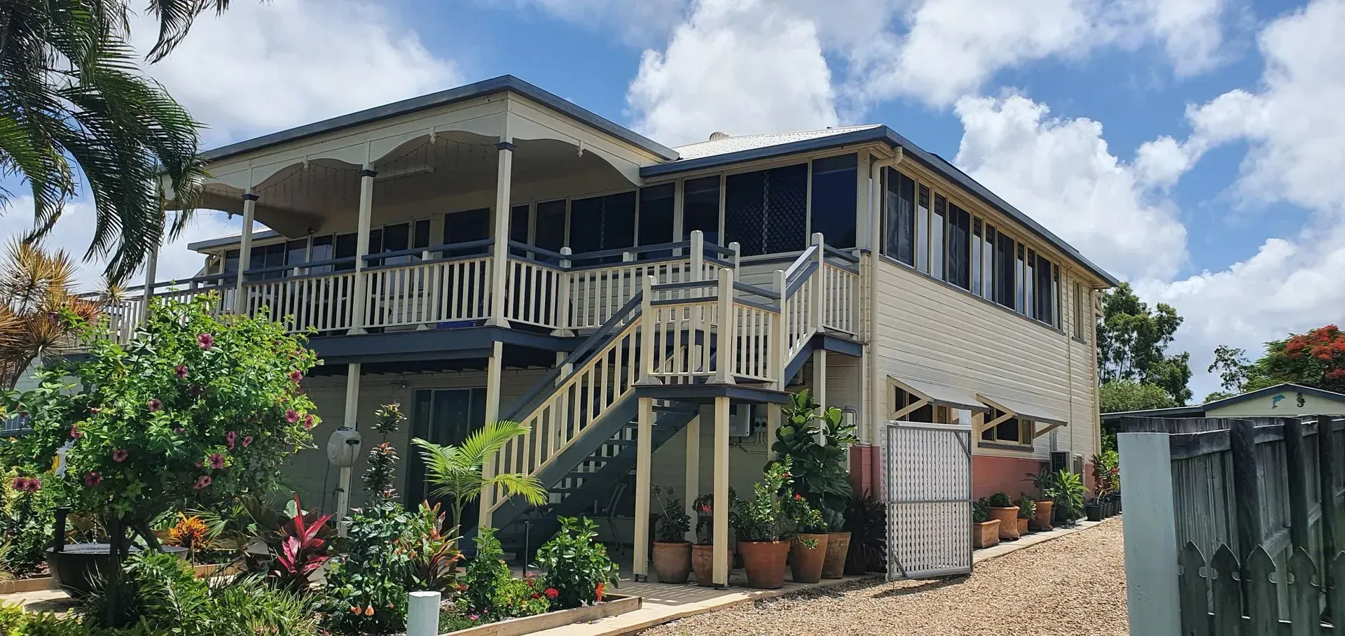 Two-story Beige House With Veranda, Stairs, and Potted Plants — Keppel Coatings in Pacific Heights, QLD