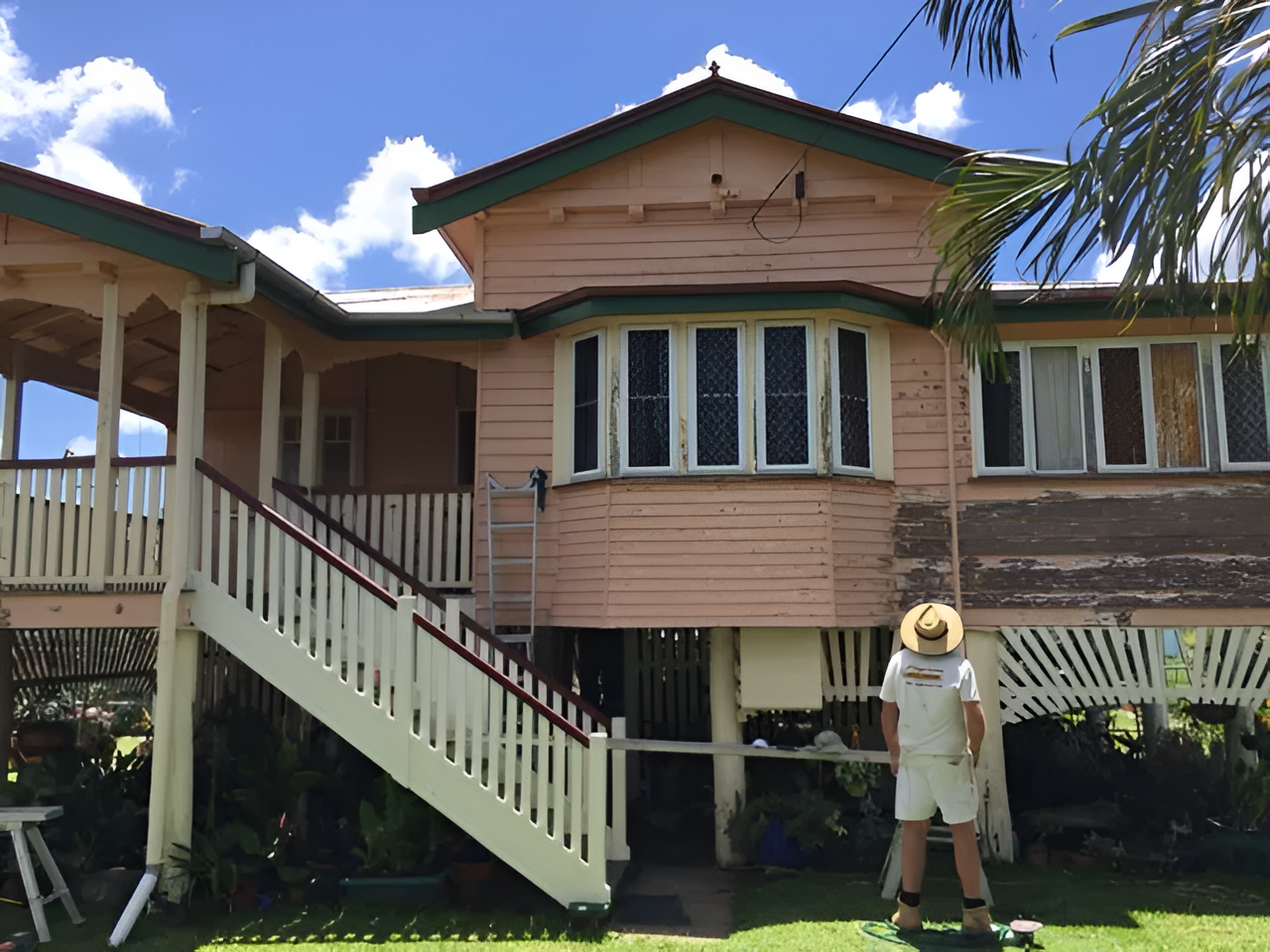 Two-story Pink House With a Porch. a Person in a Hat is Painting the Exterior — Keppel Coatings in Pacific Heights, QLD