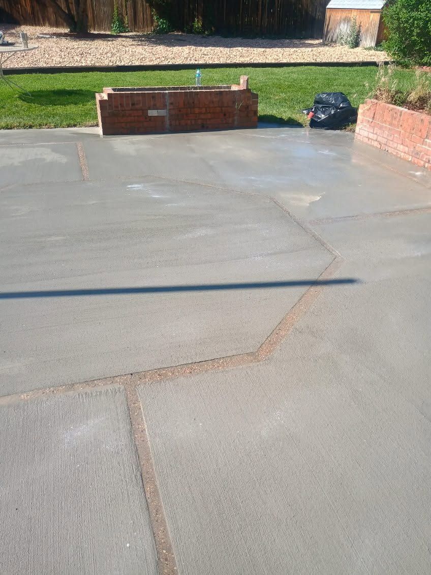 Cracked concrete patio with low brick walls, grass, and a black bag near the back edge.
