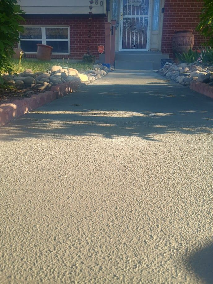 Front walkway leading to a brick house entrance, lined with low stone borders and plants.