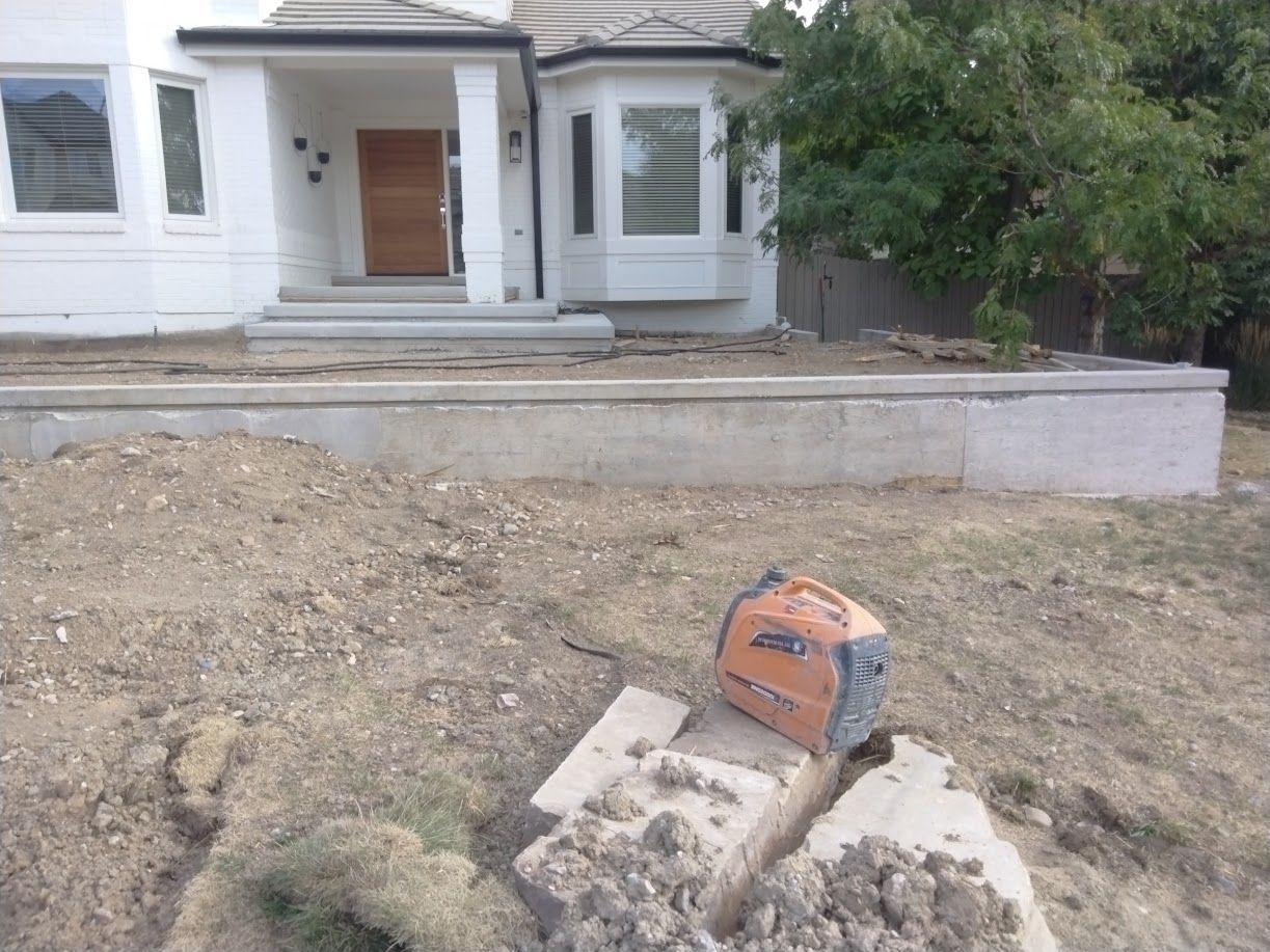 Front yard with unfinished landscaping, a house porch, and a small orange construction tool near the sidewalk.
