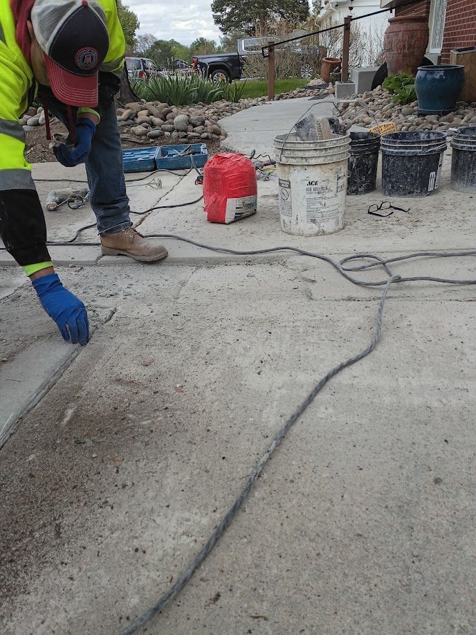 Worker smoothing wet concrete at a construction site with buckets and hoses nearby