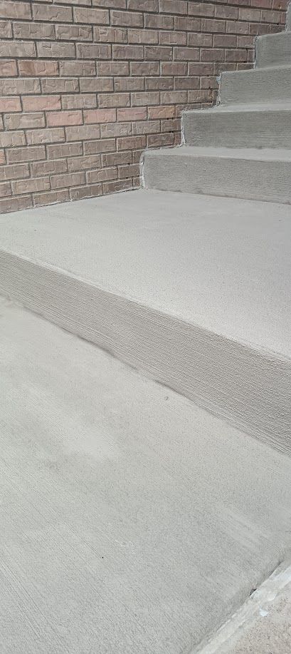 Concrete stairs beside a brick wall, with a smooth ramp-like landing in the foreground
