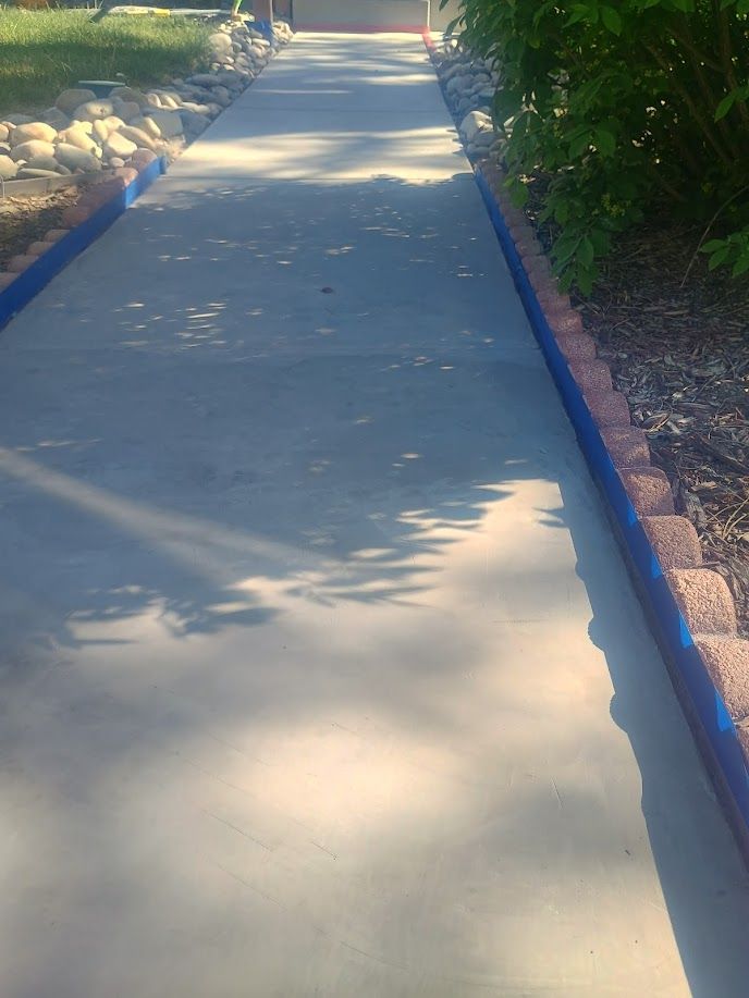 Sunny concrete walkway with blue-painted edges and dappled tree shadows