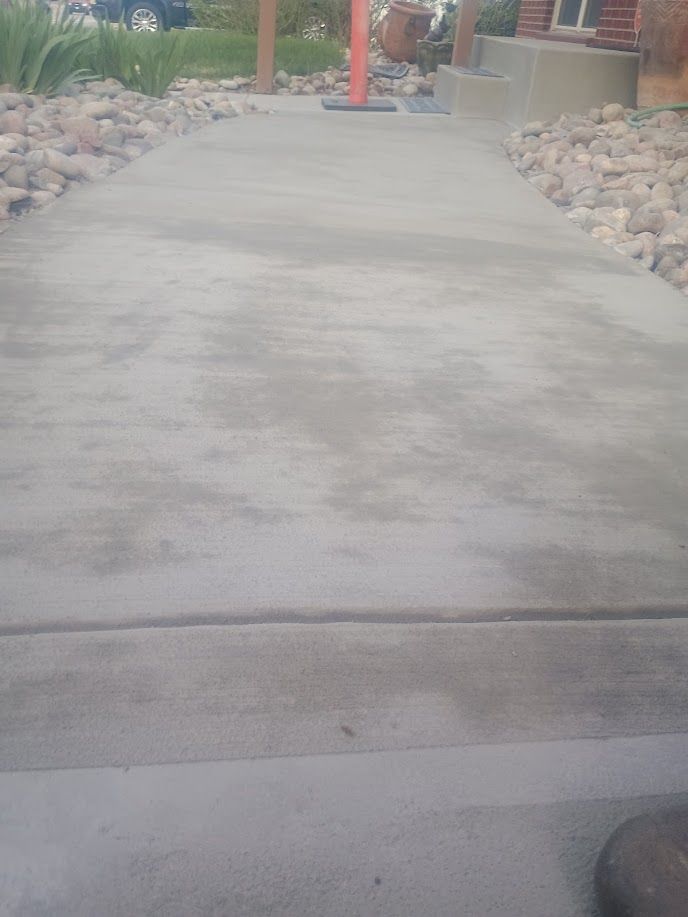 Concrete walkway with rocks along both sides leading toward a building entrance.