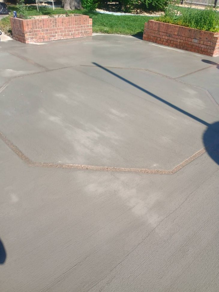 Empty concrete patio with low brick walls and a long shadow in bright sunlight