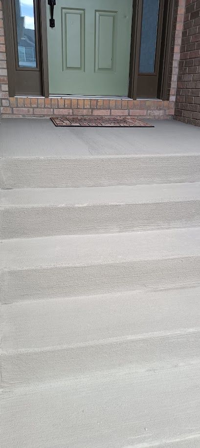Front steps leading to a green front door with brick trim and a small doormat.