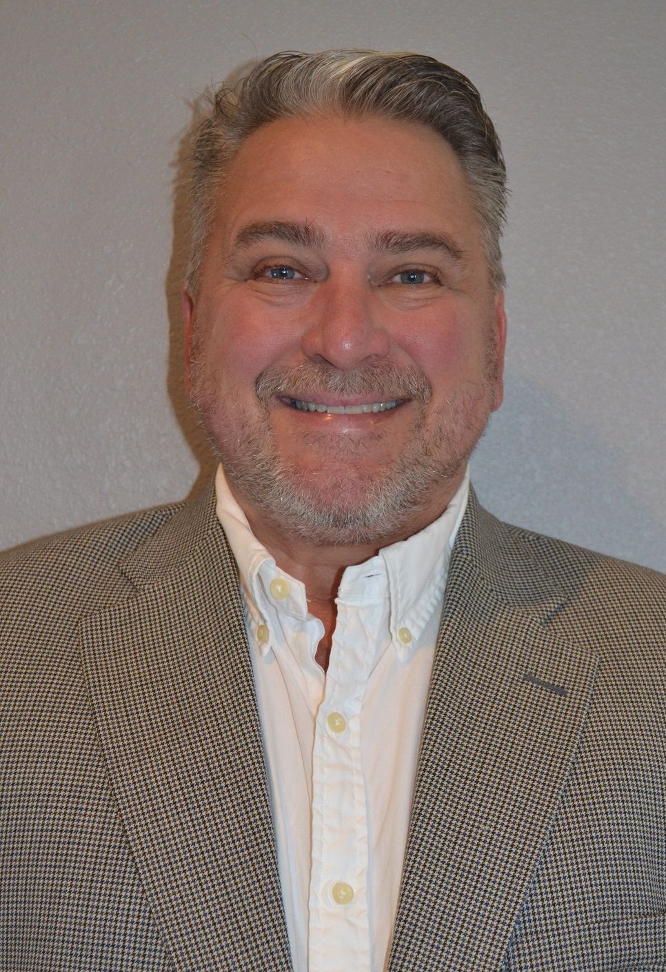 A man in a suit and white shirt is smiling for the camera.