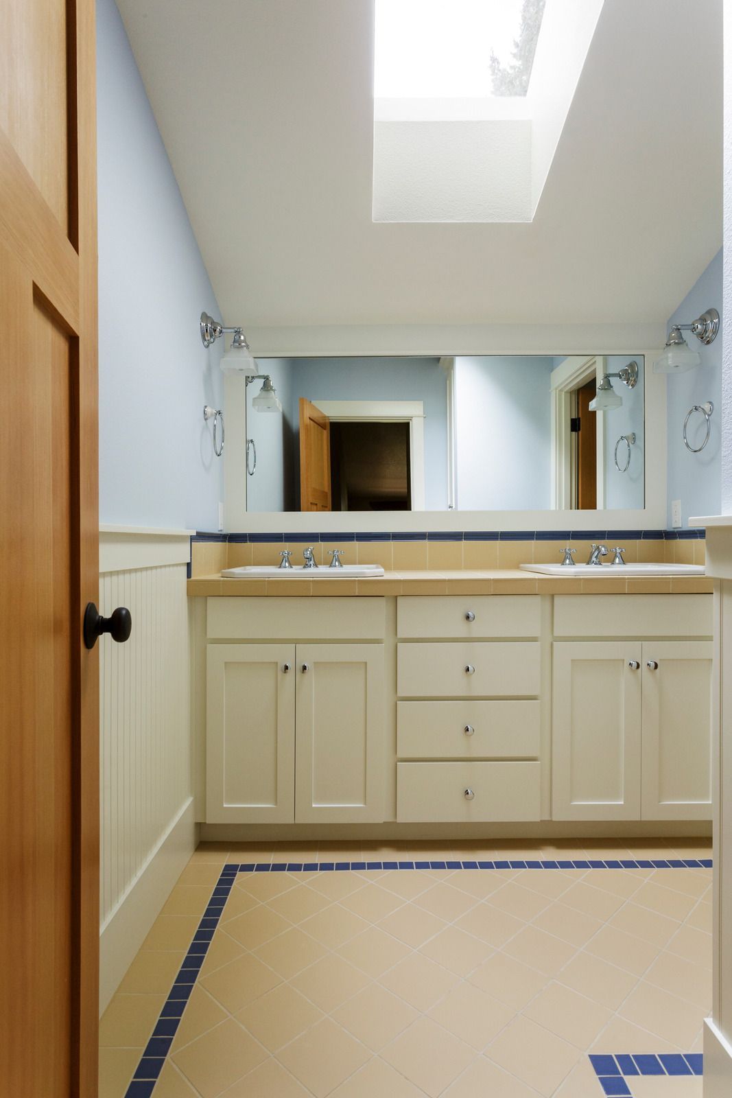A bathroom with a wooden vanity , sink , mirror and towels.