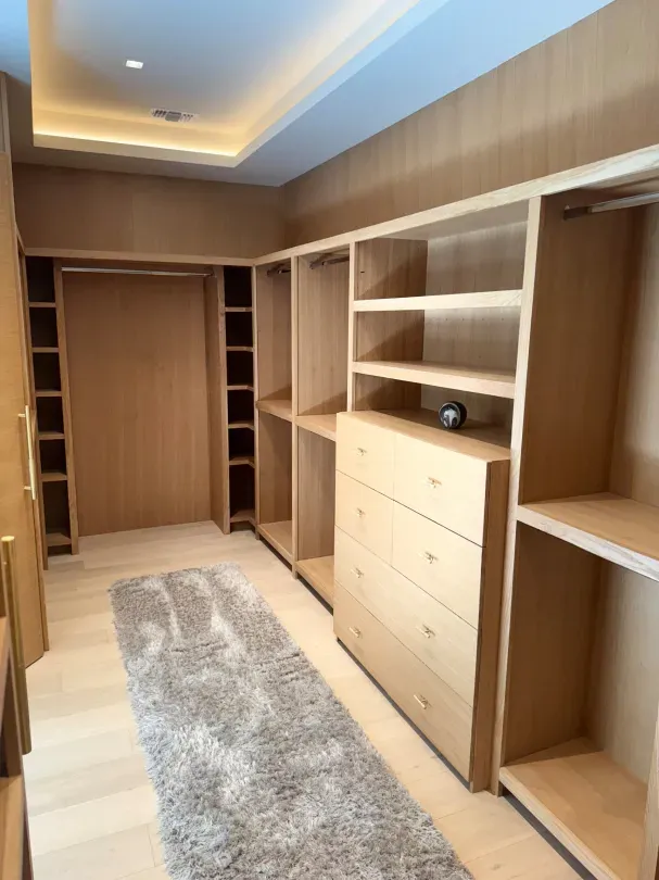 A walk in closet with lots of shelves and drawers