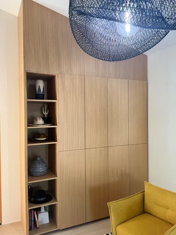 A living room with a yellow couch and a wooden shelf.