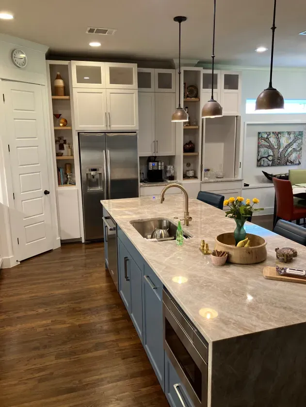 A kitchen with a large island , sink , refrigerator and stainless steel appliances.