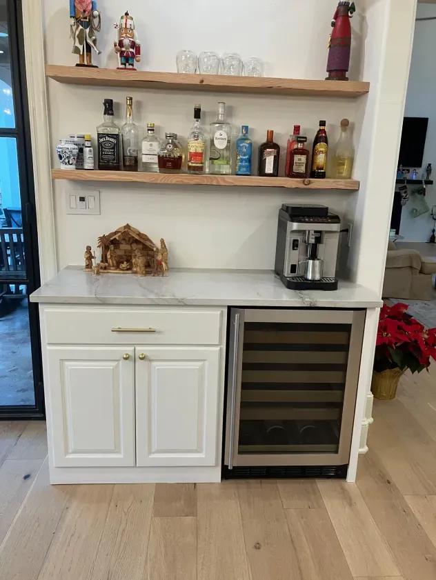 There are many bottles of alcohol on the shelves in this kitchen.