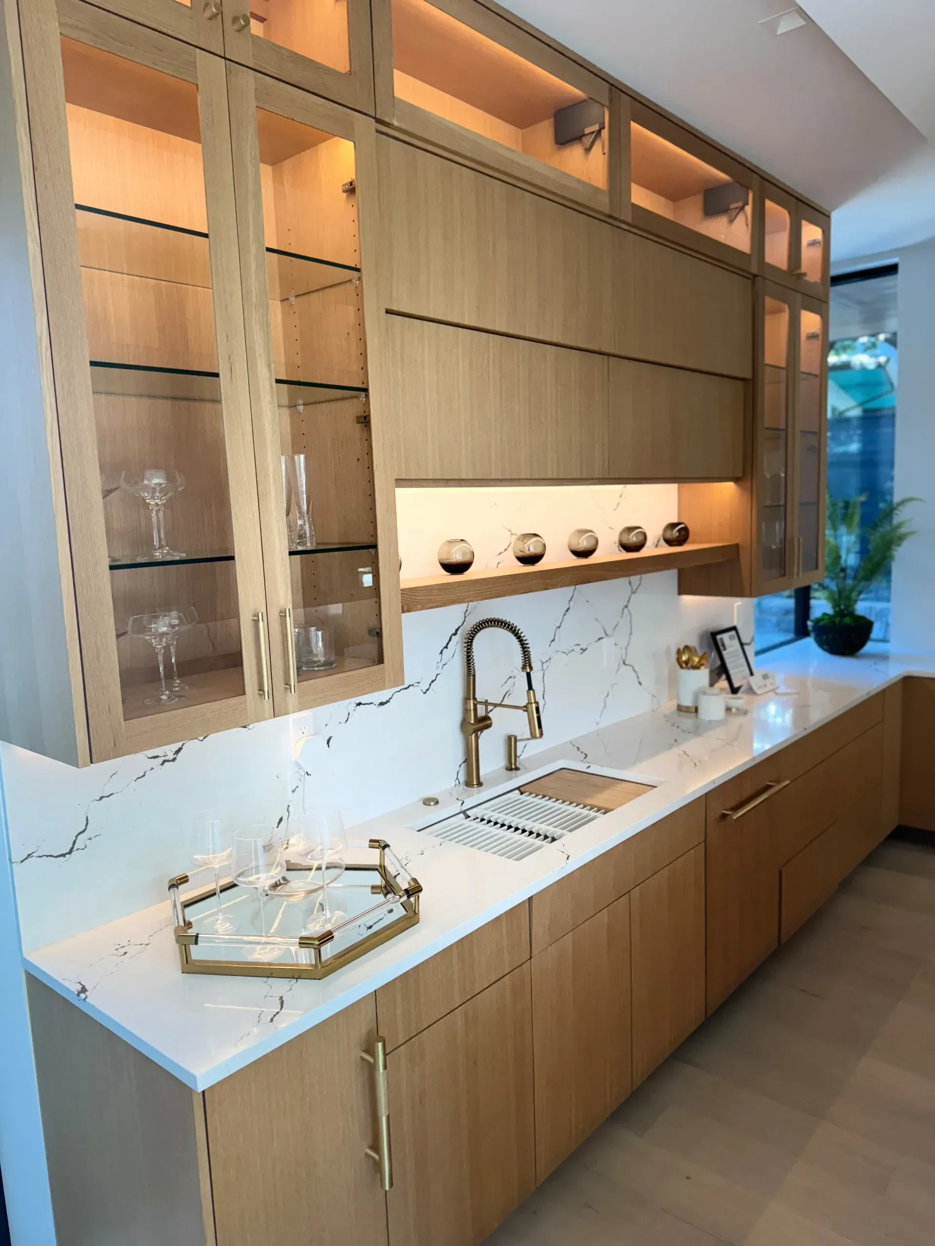 A kitchen with wooden cabinets , white counter tops , and a sink.