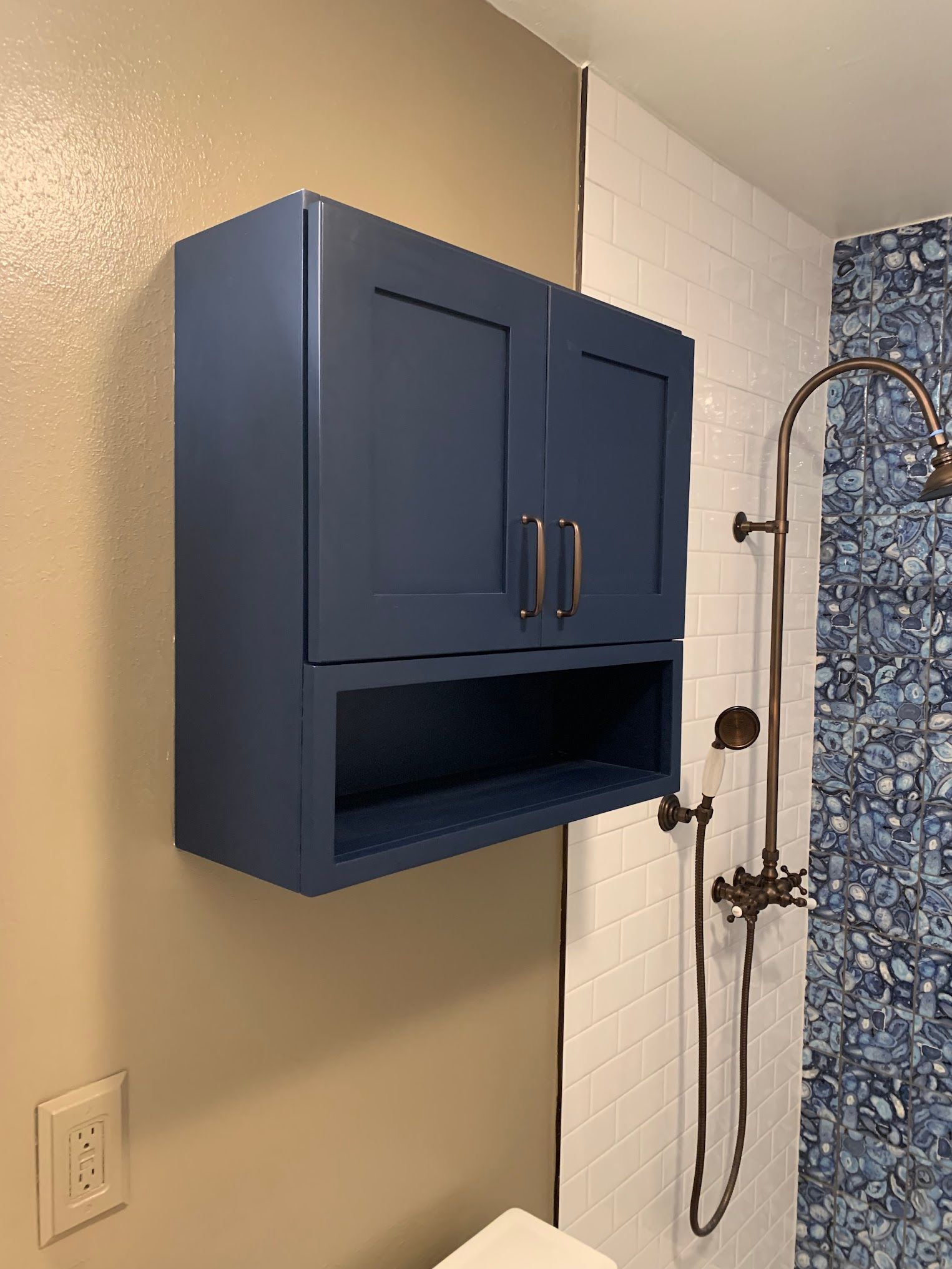 A bathroom with a blue cabinet and a shower head.