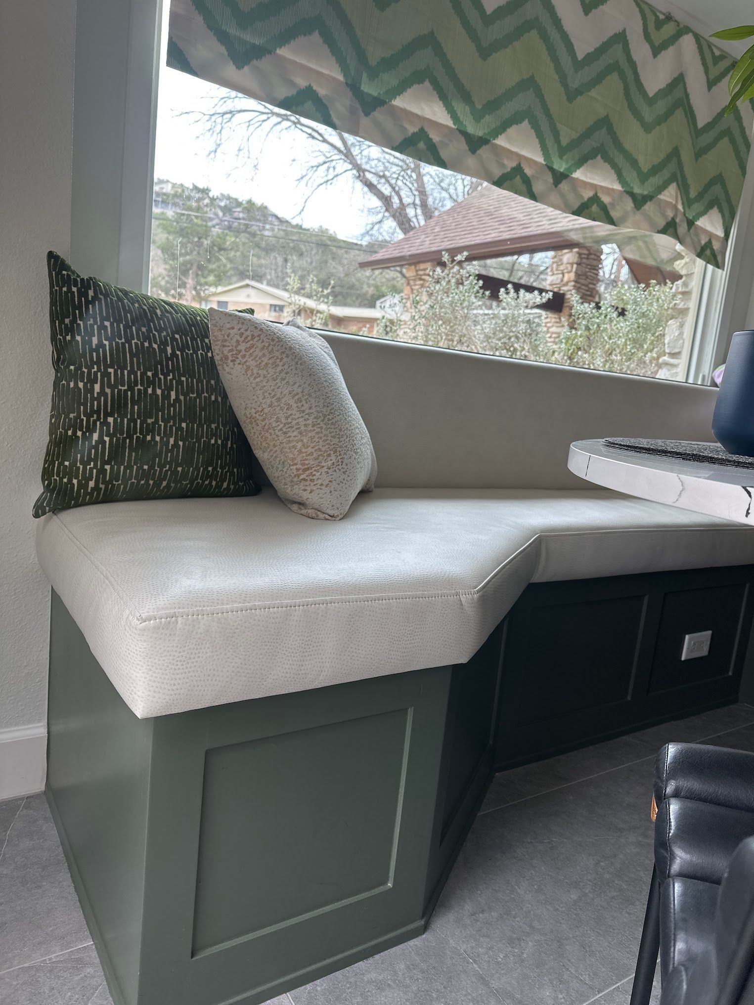 A couch with a pillow on it is in front of a window.