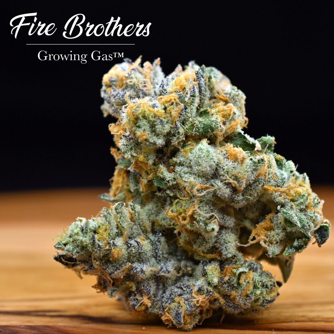 Fire Brothers cannabis bud on a wooden surface, with “Growing Grass” text in the corner
