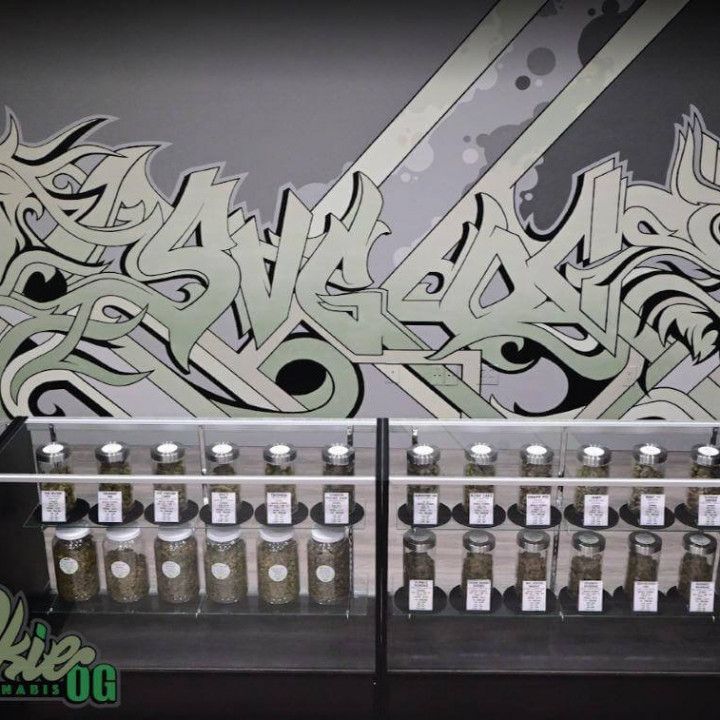 Graffiti mural above a row of small bottles on shelves in a shop display