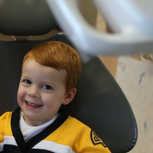 Two women and a child are sitting in a dental chair.