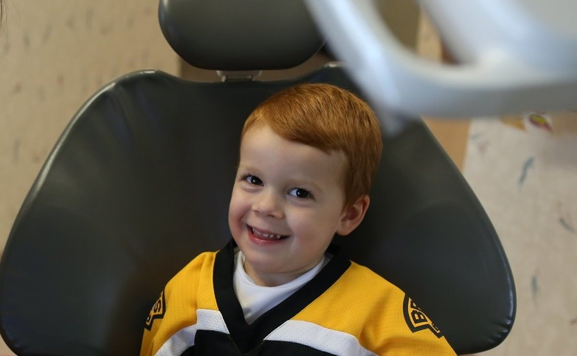 A woman is talking to a young boy in a dental chair