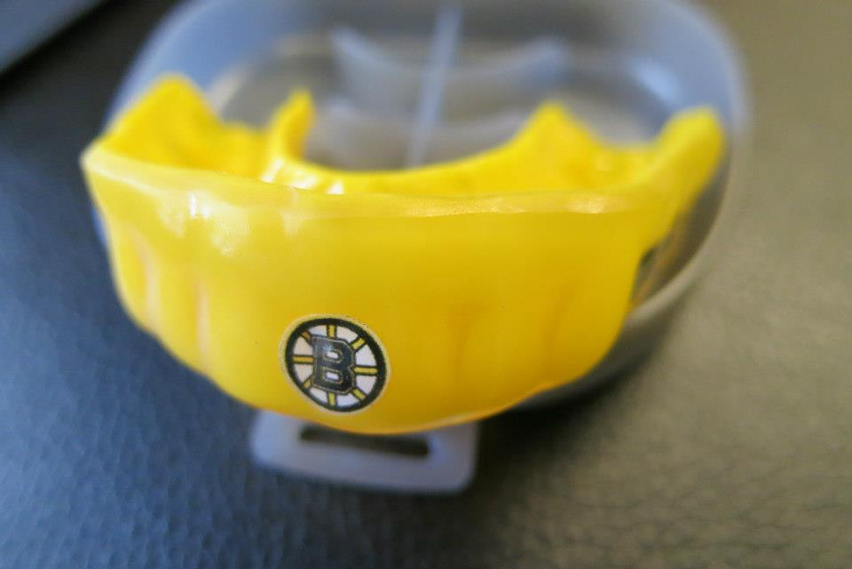 A yellow mouth guard with the boston bruins logo on it