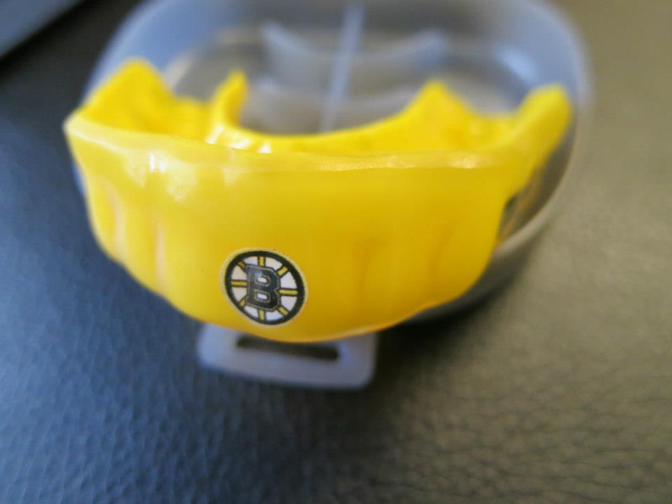 A yellow mouth guard with the boston bruins logo on it
