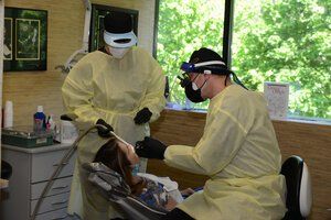 A dentist is examining a patient 's teeth in a dental office.