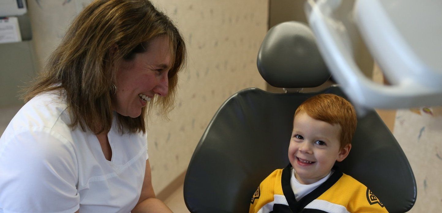 A woman is talking to a young boy in a dental chair