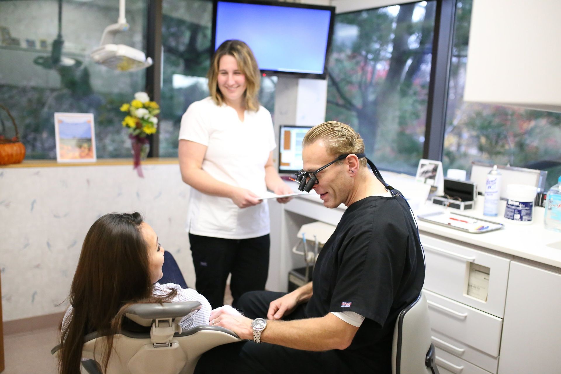 A woman is sitting in a dental chair talking to a dentist