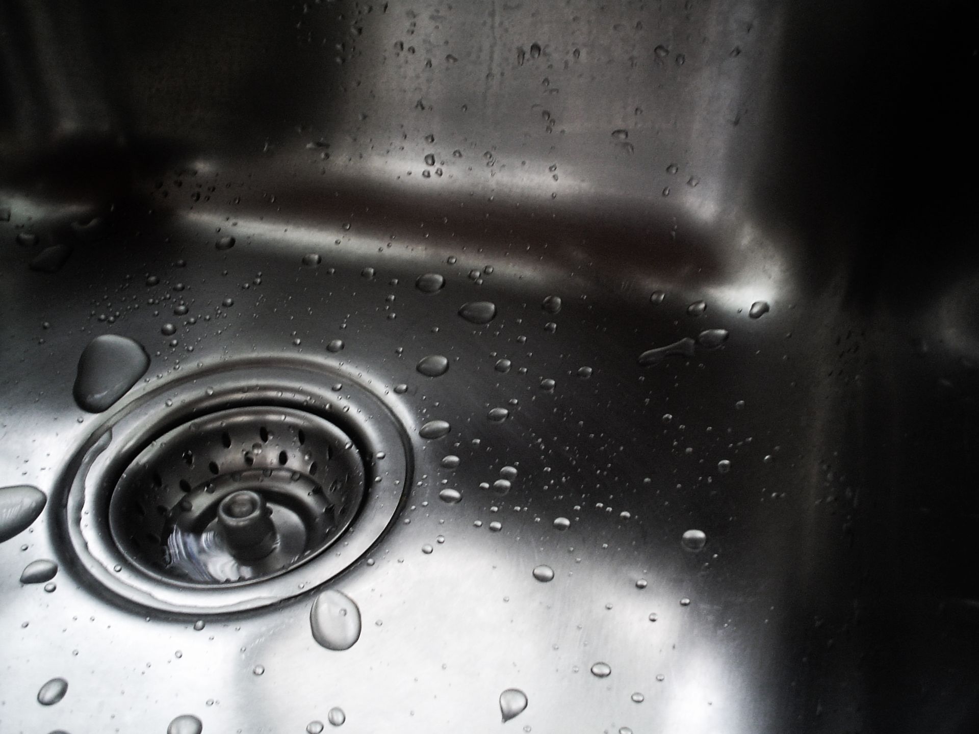 Stainless steel sink with water droplets and a drain in the basin