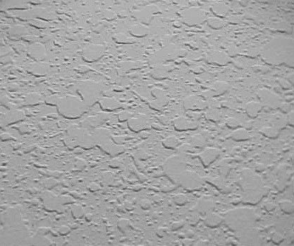 Textured, light-colored wall surface with a popcorn-like pattern.