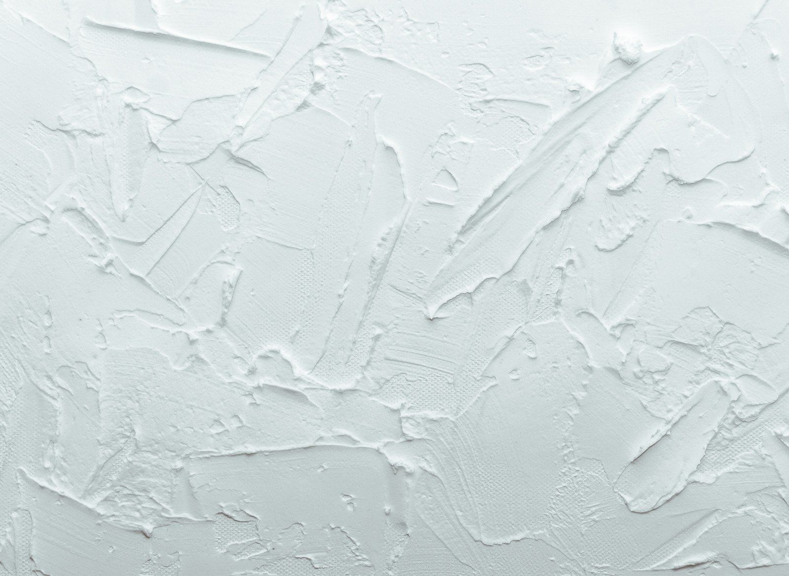 Textured, light-colored wall with visible strokes from application of the plaster, creating a rough, uneven surface.
