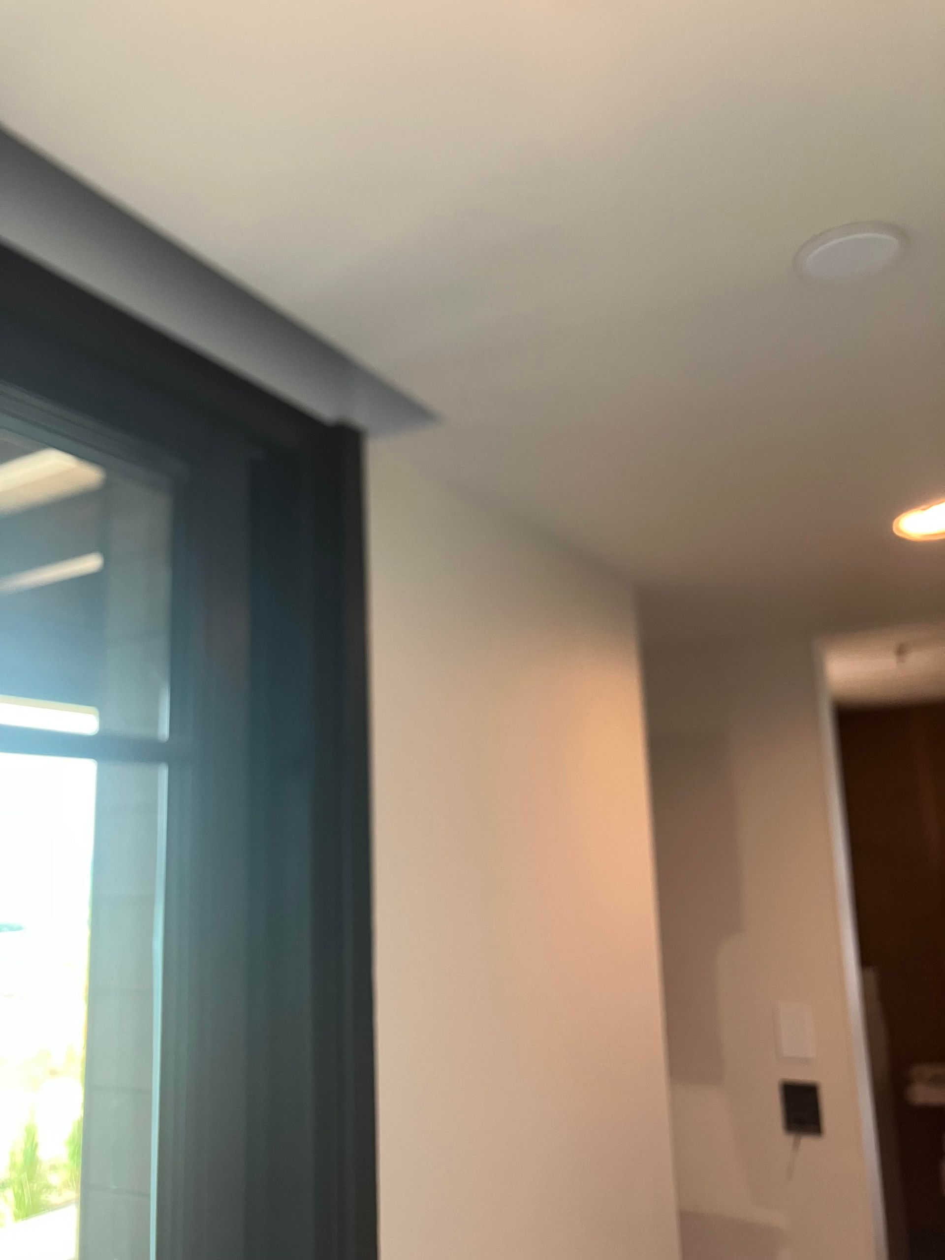 Corner of a room with a black window frame, white wall, and ceiling.