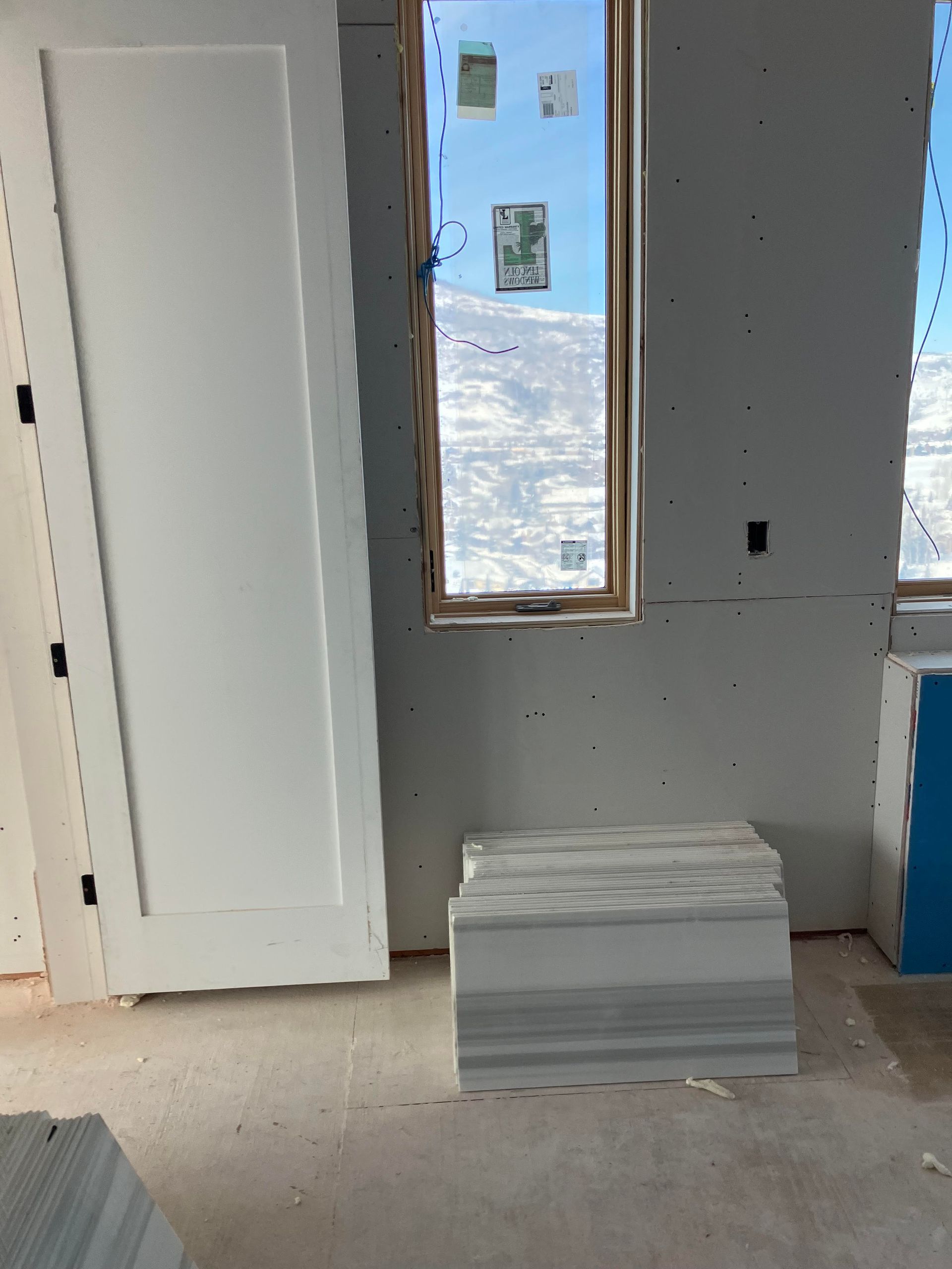 Interior with a door, window, and stacked drywall in a construction setting.