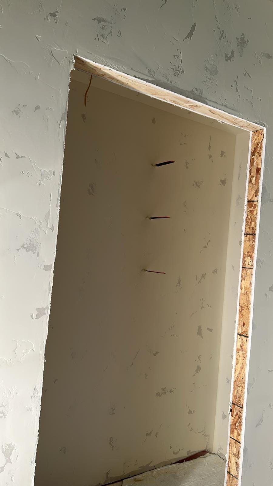 Opening in wall with wood frame, three nails visible. Painted in white.