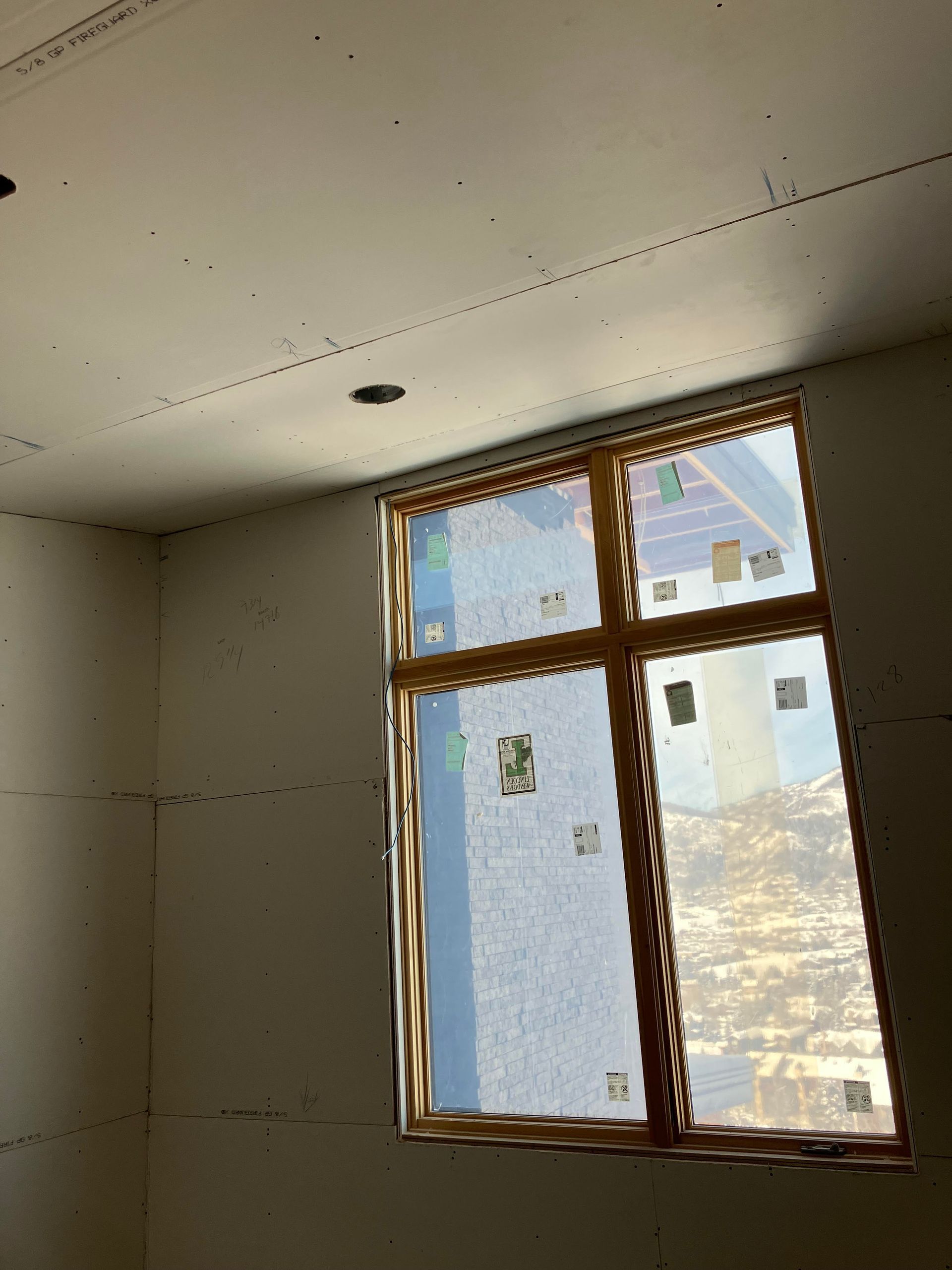 Interior room under construction with a window and drywall.