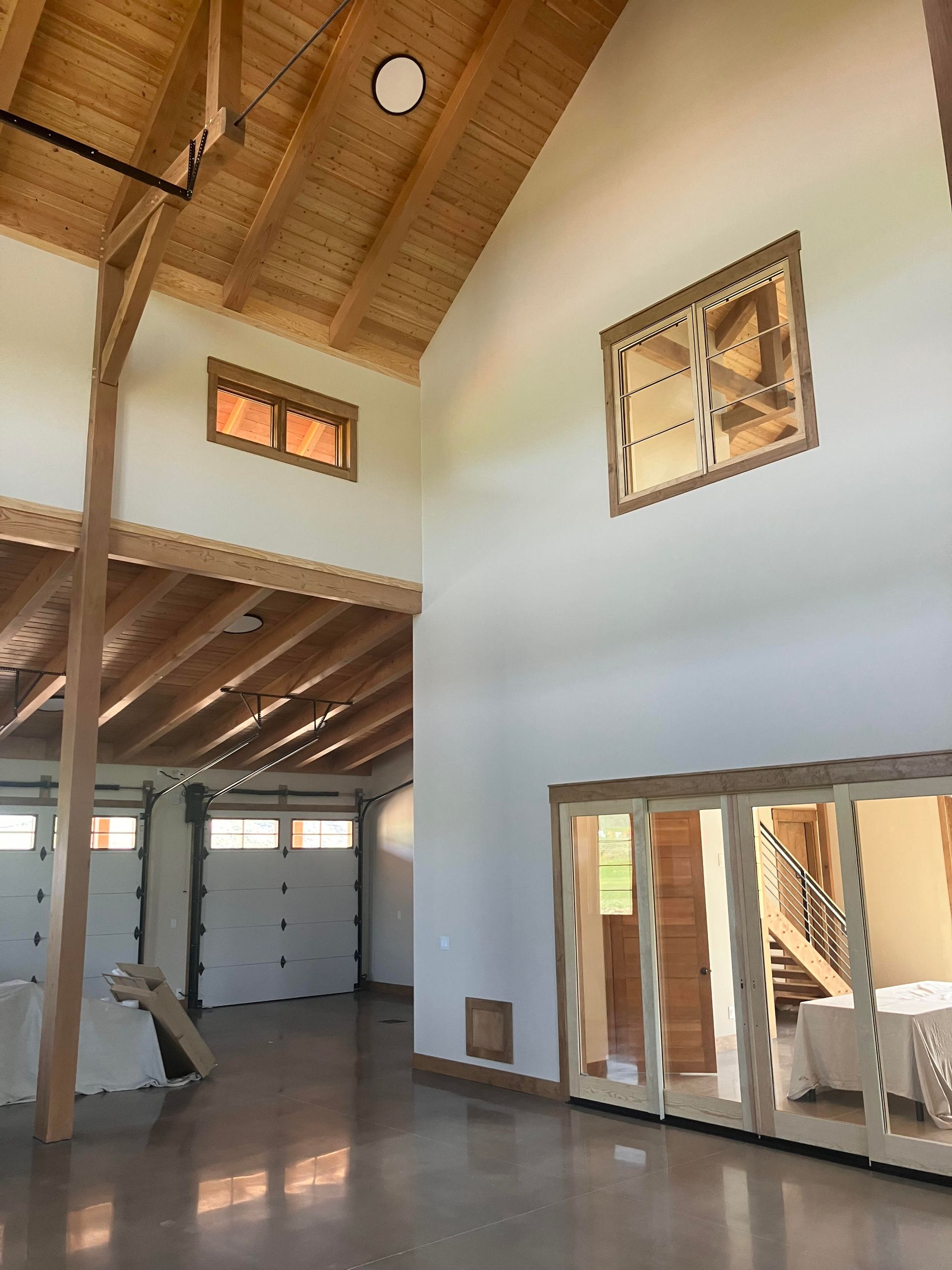 Interior of a modern building with high ceilings and wooden beams. Open doors and windows.