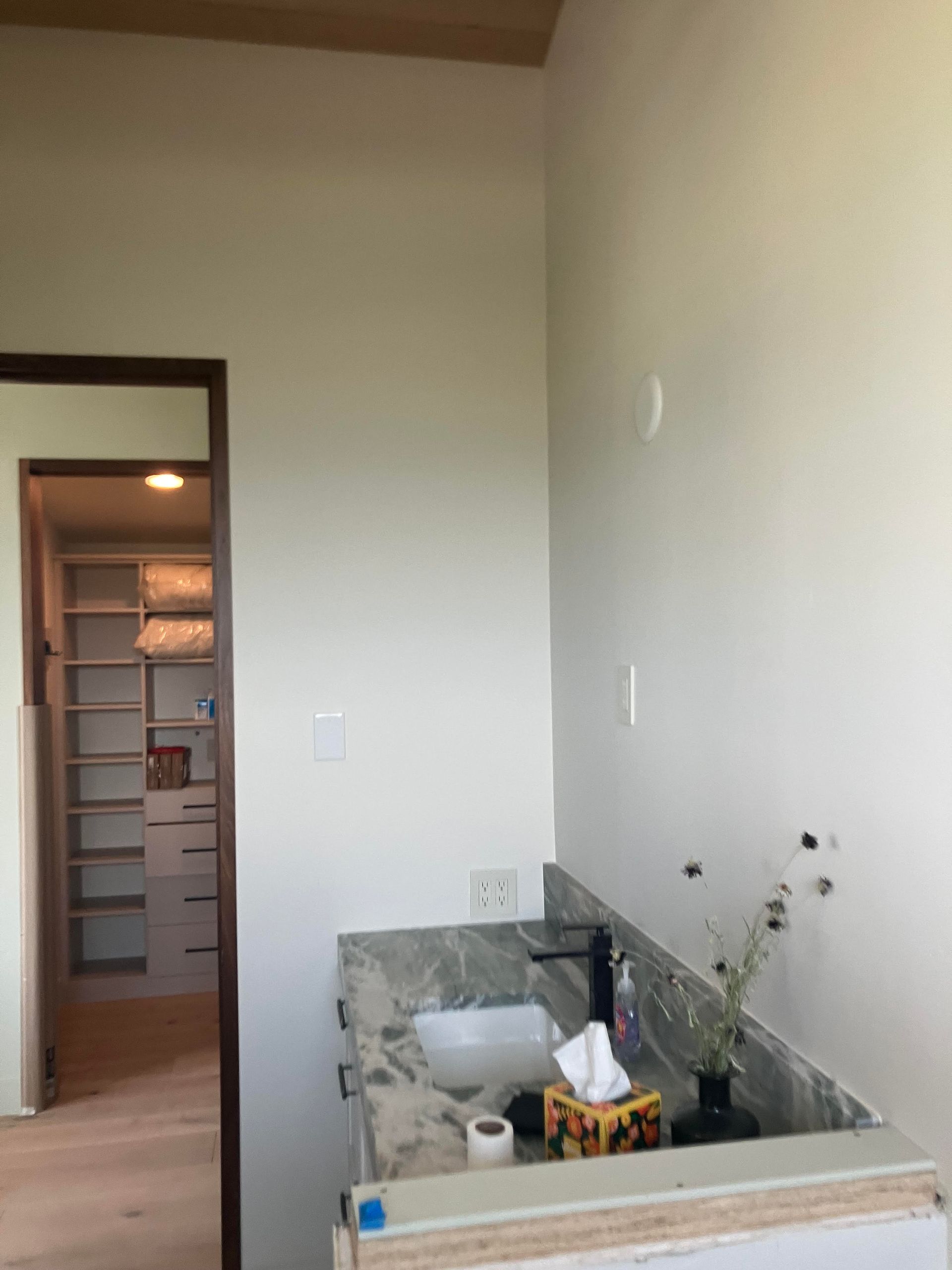 Bathroom with vanity, mirror, and closet visible through a doorway; white walls and granite countertop.