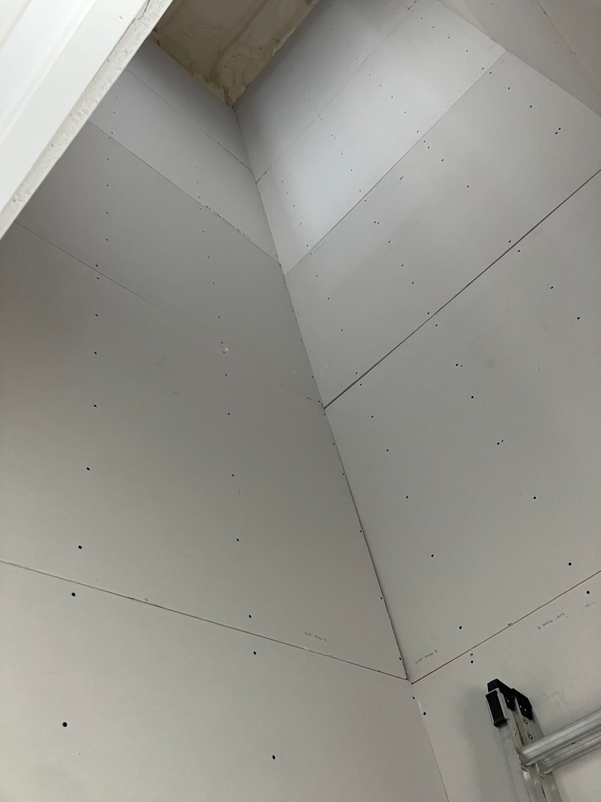 Interior corner with white drywall and a metal ladder.