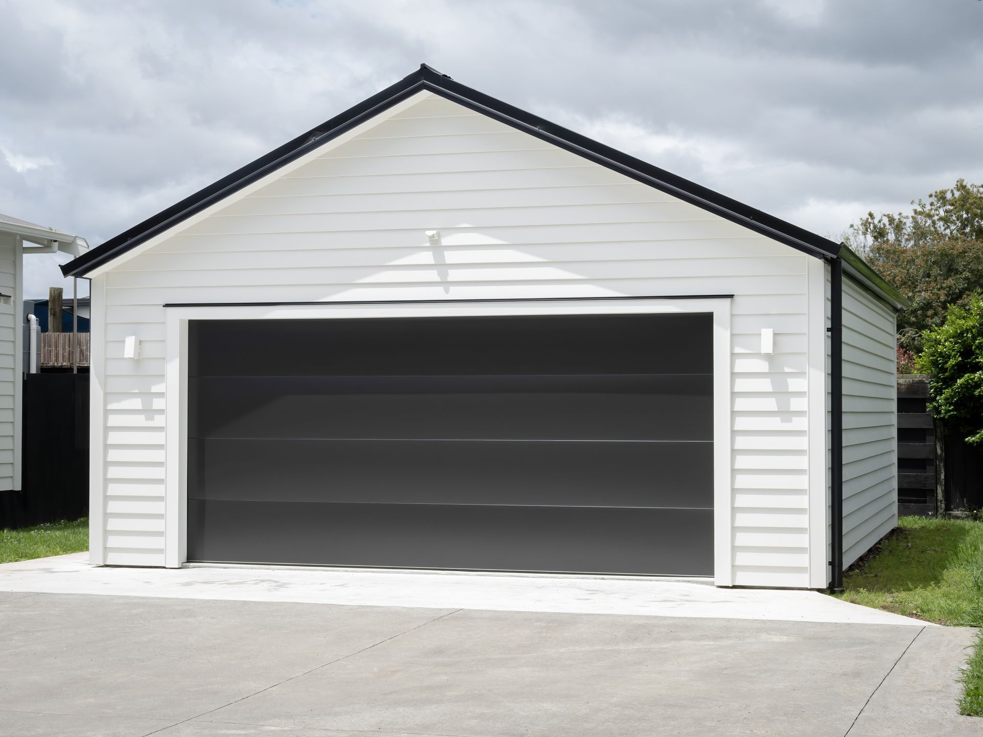 White gable-roof double garage with dark gray door built by a metal garage builder.