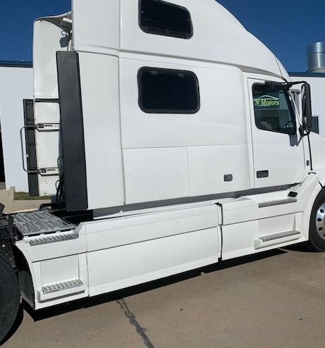 White semi-truck with sleeper cab parked outside.