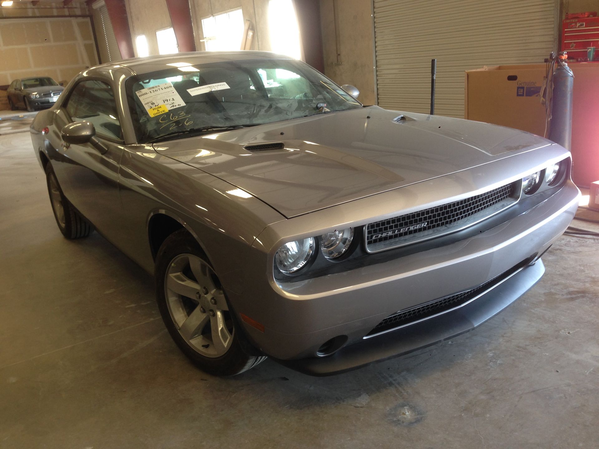 Silver Dodge Challenger coupe parked inside a warehouse.