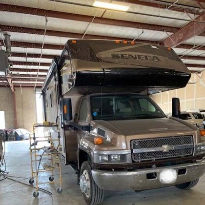 Brown and black Seneca RV parked in a garage.