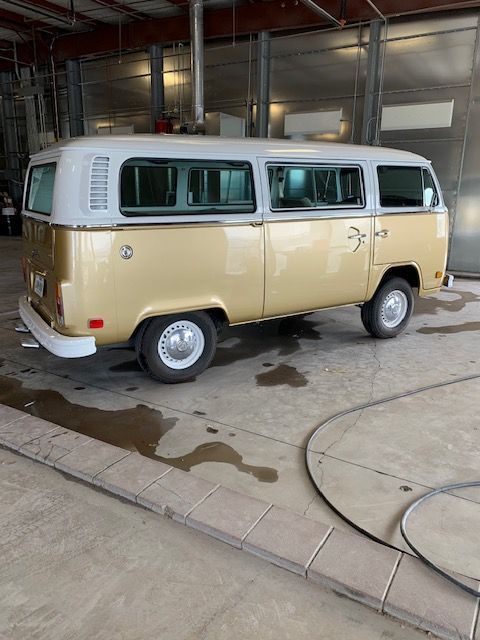 Two-tone gold and white Volkswagen bus parked in a garage.