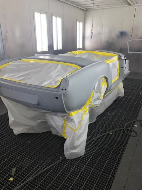 Car body primed and masked in a spray booth, ready for painting.