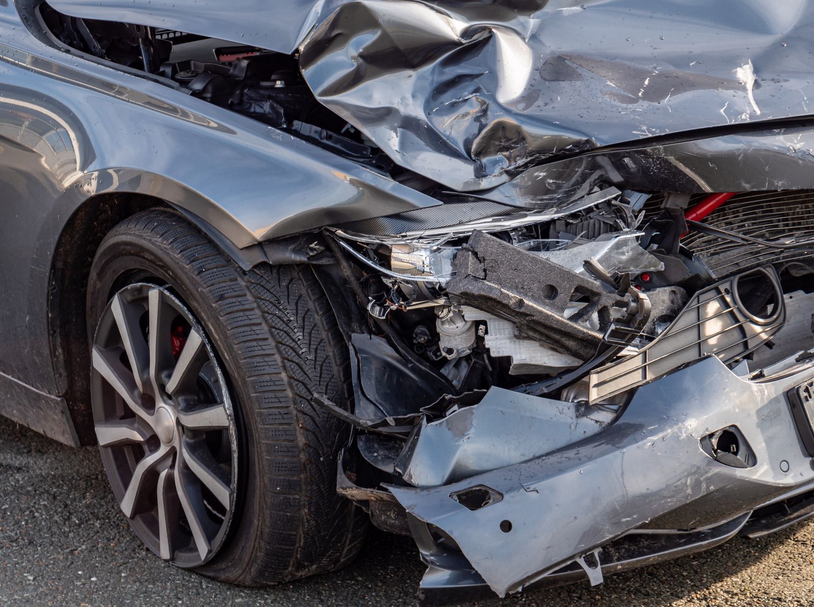 Damaged gray car, front end crushed, showing severe collision damage.
