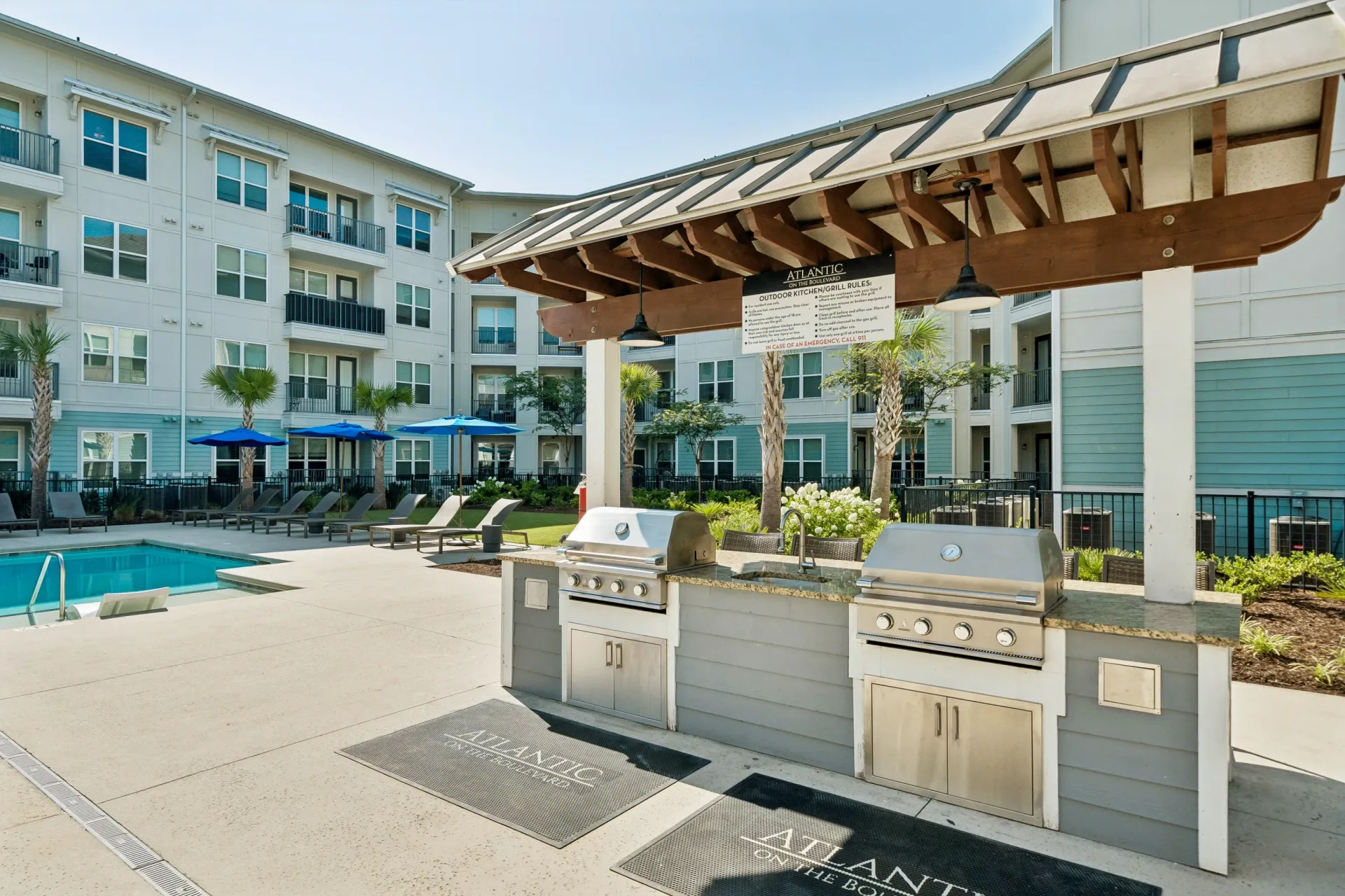 Outdoor kitchen and pool area with grills, seating, and lounge chairs at Atlantic on the Boulevard in North Charleston, SC.