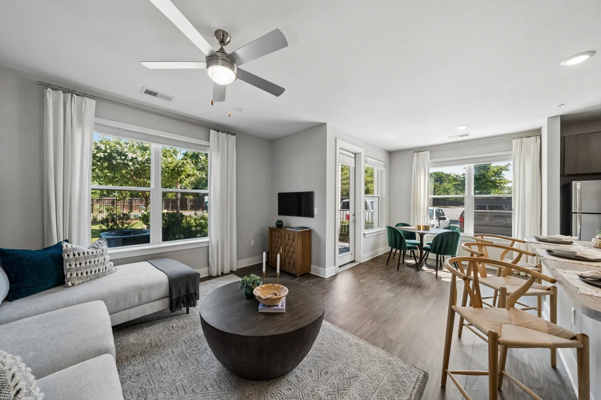 Modern living and dining area with large windows, ceiling fan, and stylish furniture at Atlantic on the Boulevard in North Charleston, SC.