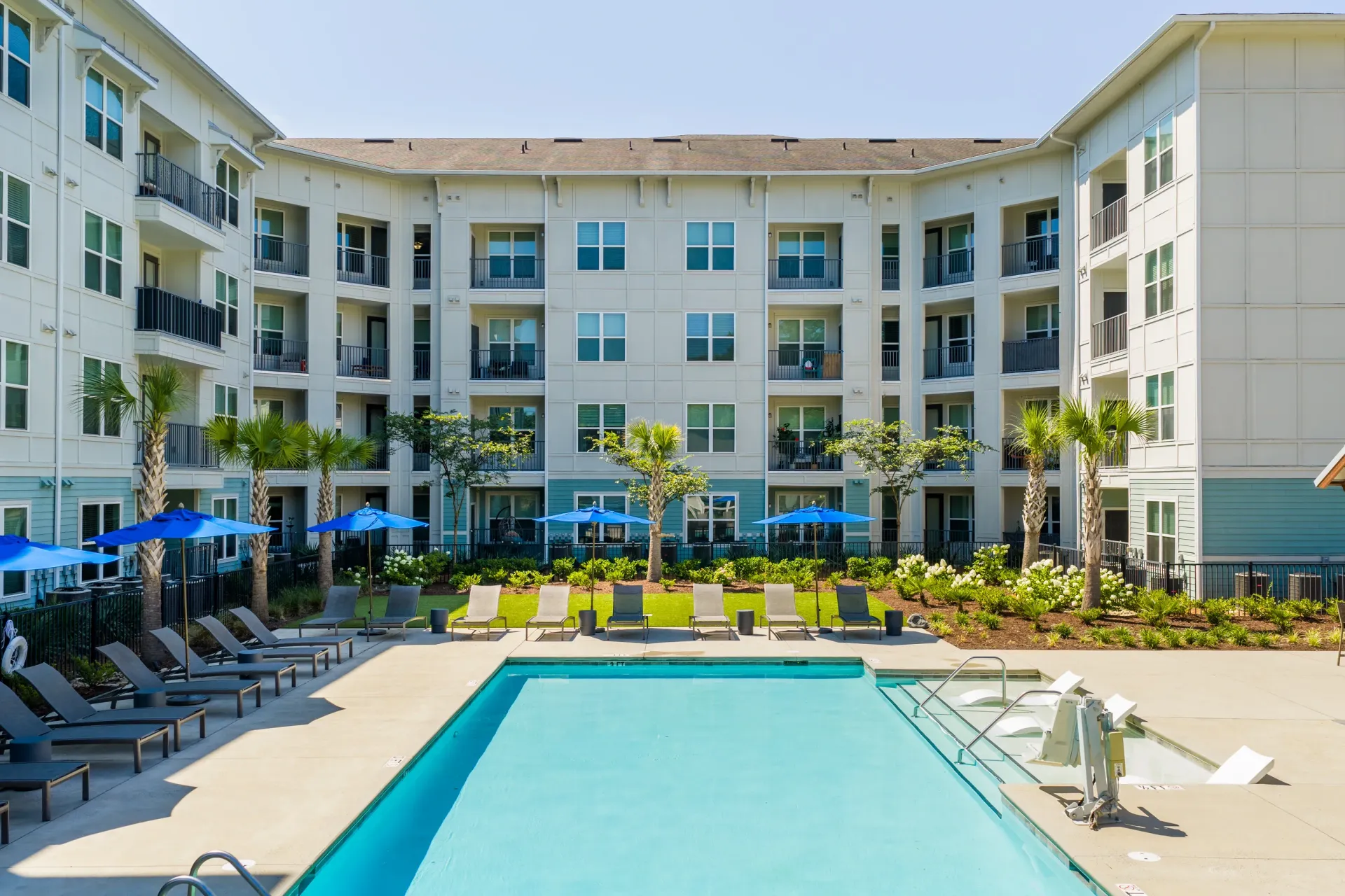 Apartment building courtyard with a swimming pool and lounge chairs.