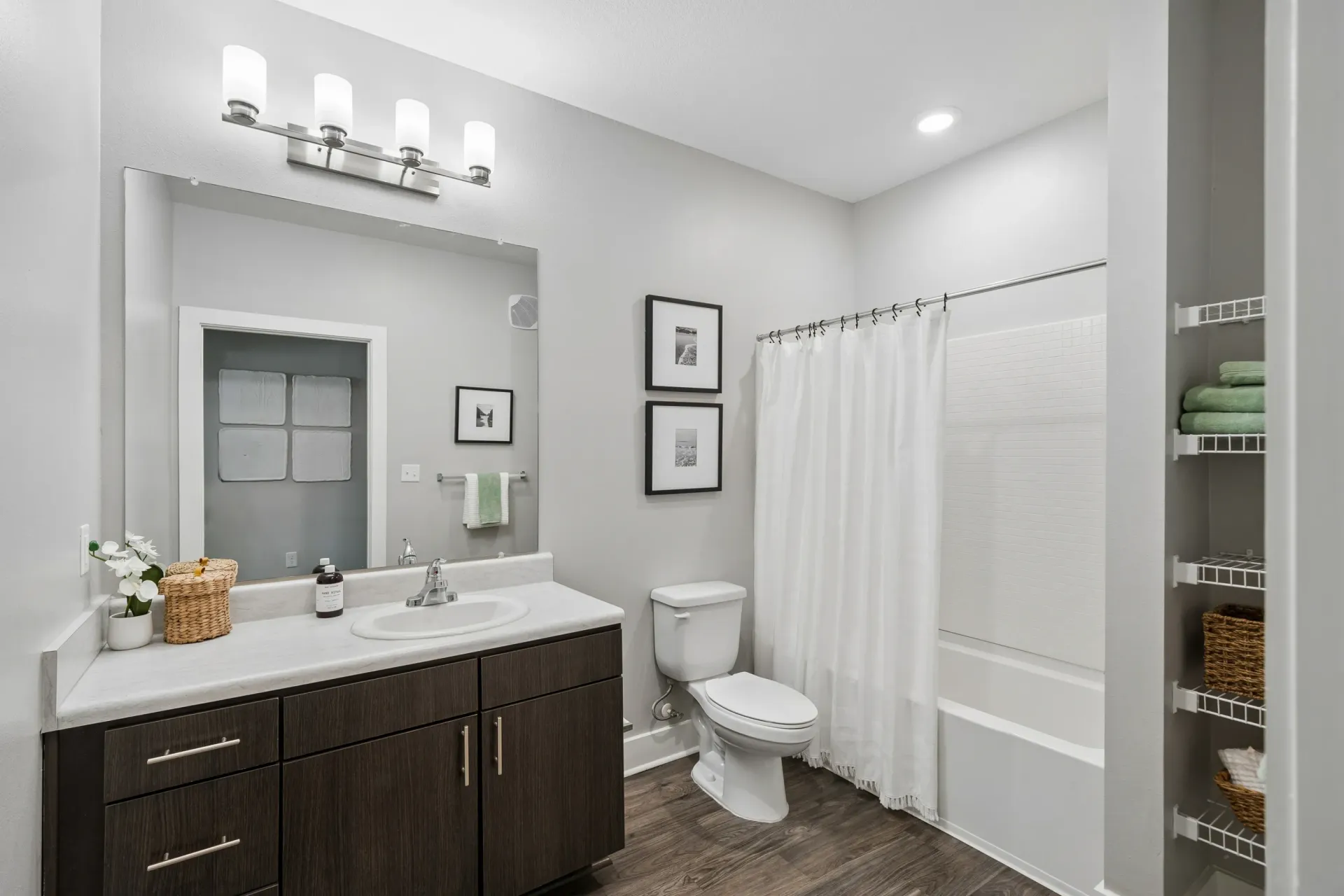 Modern bathroom with dark wood vanity, white countertop, and stainless steel fixtures at Atlantic on the Boulevard in North Charleston, SC.